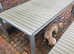Light grey wooden effect slat table with silver legs and trim and matching two benches